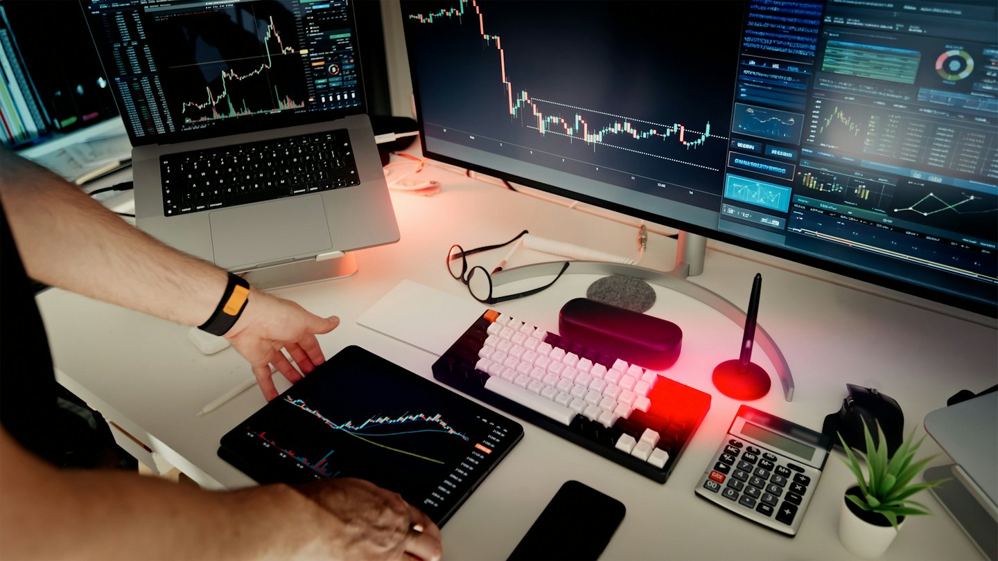 Handen die een tablet met financiële grafieken gebruiken in een modern kantoor.